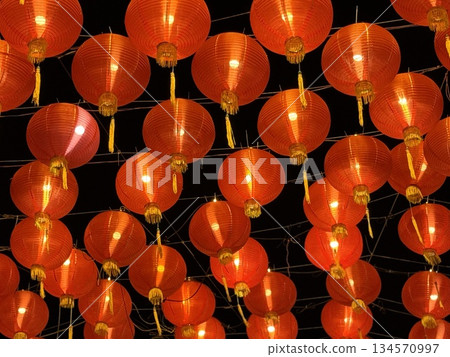 Vibrant red Chinese lanterns glow against a dark night, creating a warm, festive atmosphere perfect for celebrations, festivals, and cultural events. Ideal for mood setting, decoration, and seasonal 134570997