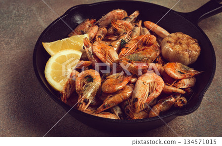 Fried shrimps, in a cast-iron pan, shrimps for beer, in a newspaper, on a gray table, there are no people, 134571015