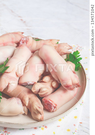 Pork trotters arranged on a plate with fresh parsley on a white background Pork trotters arranged on a plate with fresh parsley on a white background 134571042