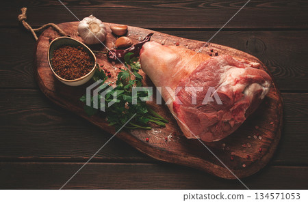 Raw pork knuckle, on a wooden chopping board, with spices, close-up, top view, no people, 134571053