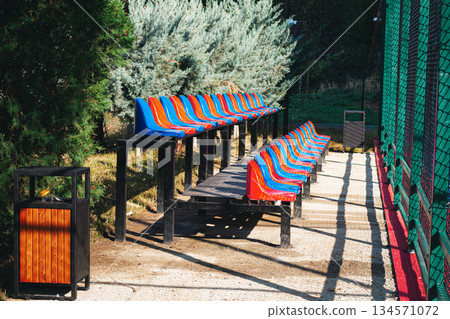 Colorful seating area near a sports field in a park during a sunny day Colorful seating area near a sports field in a park during a sunny day 134571072