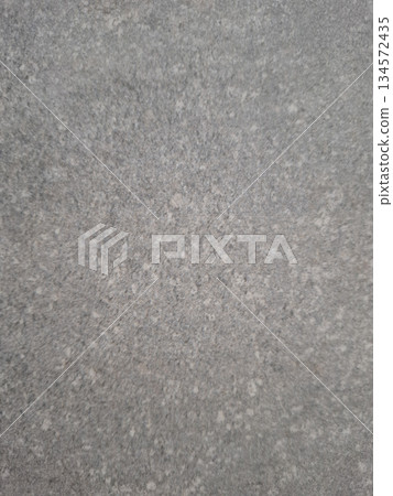 The scene shows a neutral gray background that features subtle patterns and variations in texture. The surface appears even and uniform throughout without any distinct features. 134572435