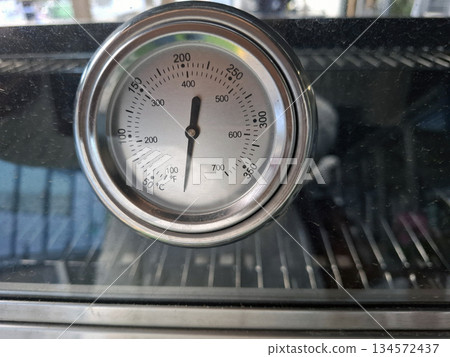 A temperature sensor is attached to an electric grill to show the internal heat level. This tool helps in cooking meat and vegetables properly while grilling outside. 134572437