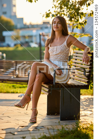 Slavic Woman in White Dress on Park Bench Slavic Woman in White Dress on Park Bench 134572469