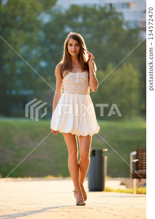 Slavic Woman Walking in Sunlit Urban Park Slavic Woman Walking in Sunlit Urban Park 134572470