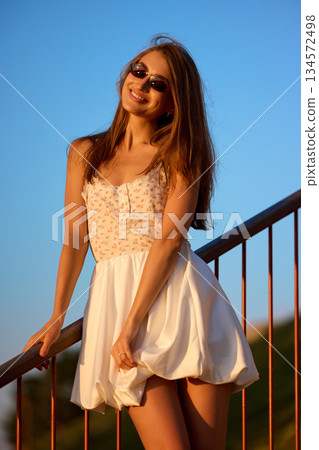Slavic Woman in White Dress on Railing Slavic Woman in White Dress on Railing 134572498