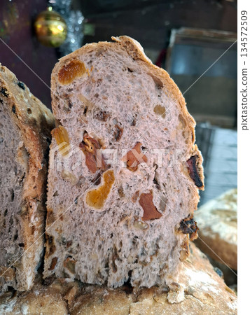 Bread is sliced to show pieces of dried fruit inside. This homemade item is offered at a farmers market where visitors explore local foods and products. Bread is sliced to show pieces of dried fruit inside. This homemade item is offered at a farmers market where visitors explore local foods and products. 134572509