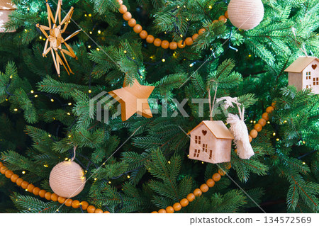 Handmade craft holiday Christmas ornaments on festive green spruce tree, natural wooden rustic decor 134572569