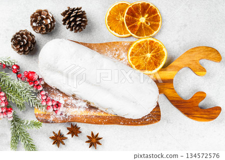 Traditional Christmas Stollen, sweet fruit loaf with sugar icing on wooden board and festive decor 134572576