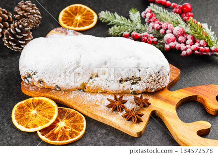Traditional Christmas Stollen, sweet fruit loaf with sugar icing on wooden board and festive decor Traditional Christmas Stollen, sweet fruit loaf with sugar icing on wooden board and festive decor 134572578