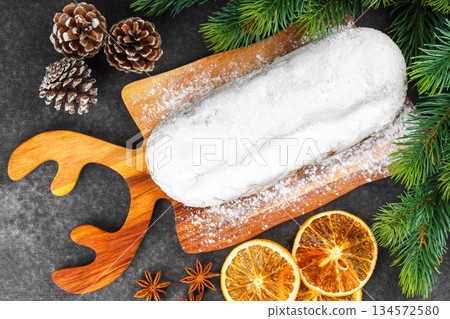 Traditional Christmas Stollen, sweet fruit loaf with sugar icing on wooden board and festive decor Traditional Christmas Stollen, sweet fruit loaf with sugar icing on wooden board and festive decor 134572580