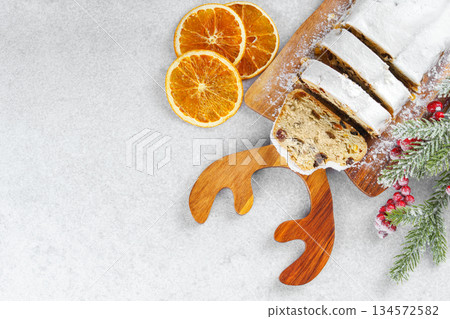 Traditional sliced Christmas stollen loaf with raisins and powdered sugar on wooden cutting board 134572582