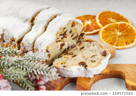 Traditional sliced Christmas stollen loaf with raisins and powdered sugar on wooden cutting board Traditional sliced Christmas stollen loaf with raisins and powdered sugar on wooden cutting board 134572583