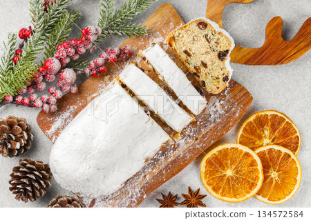 Traditional sliced Christmas stollen loaf with raisins and powdered sugar on wooden cutting board Traditional sliced Christmas stollen loaf with raisins and powdered sugar on wooden cutting board 134572584