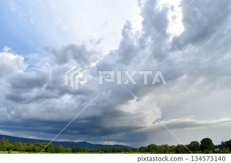 A large cloud from the storm was forming a dark gray rain cloud. over the fields and mountains 134573140
