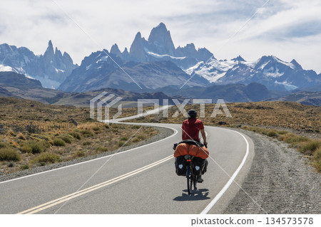 Cyclist riding winding road toward El Chalten with Fitz Roy massif, Argentina Cyclist riding winding road toward El Chalten with Fitz Roy massif, Argentina 134573578
