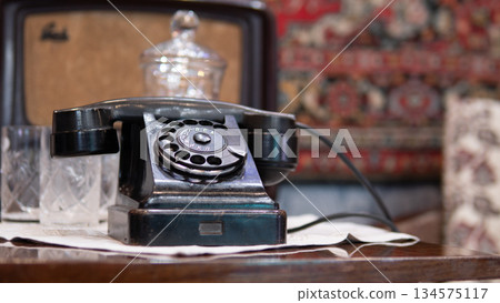 Antique rotary telephone in shop display, crystal decanter and mirrored backing create layered vintage scene, patterned rug and ornate fabric suggest curated showroom, warm reflections Antique rotary telephone in shop display, crystal decanter and mirrored backing create layered vintage scene, patterned rug and ornate fabric suggest curated showroom, warm reflections 134575117