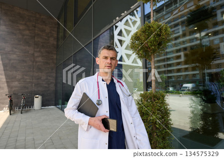 Health professional outside modern medical facility in urban setting during sunny day Health professional outside modern medical facility in urban setting during sunny day 134575329