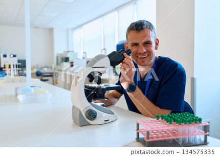 Scientist examining samples with microscope in a bright lab during a research session 134575335
