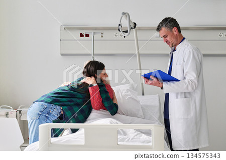 Family support in a hospital room during a patient's recovery process with a doctor providing updates 134575343