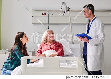 Family visits patient in hospital room during afternoon consultation with doctor discussing care and recovery options Family visits patient in hospital room during afternoon consultation with doctor discussing care and recovery options 134575400