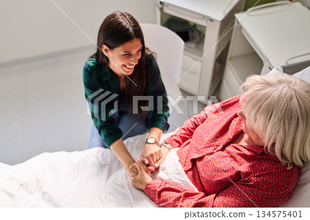 Caring interaction between family member and patient in hospital room during daytime visit 134575401
