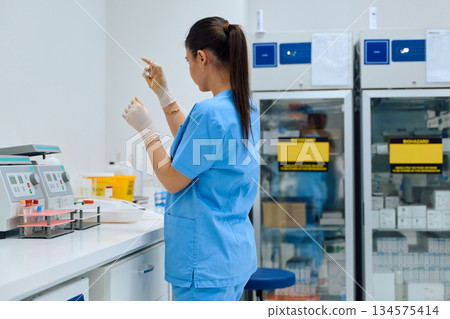 Medical professional prepares lab sample in a modern laboratory setting during daytime Medical professional prepares lab sample in a modern laboratory setting during daytime 134575414