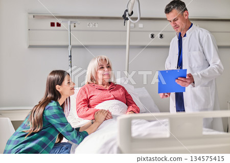 Caring nurse speaks with patient and family in a hospital room during consultation about health 134575415