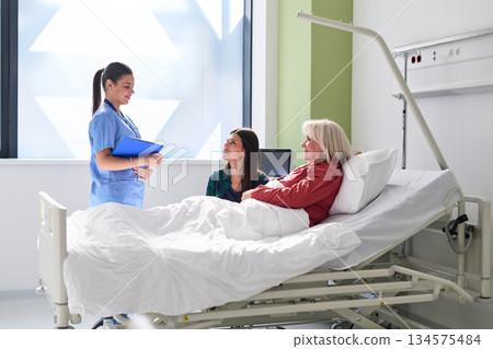 Nurse interacts with female patients in a hospital room during a morning visit Nurse interacts with female patients in a hospital room during a morning visit 134575484