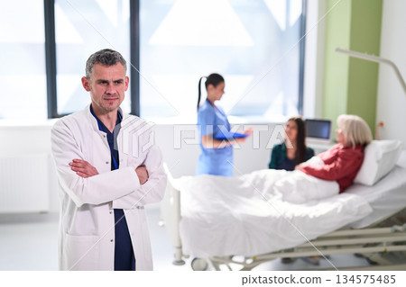 Doctor oversees patient care in hospital with nurses providing assistance and support during treatment process 134575485