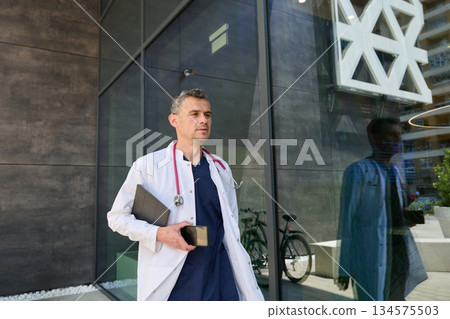 Doctor leaving modern healthcare building after a busy day in the city 134575503