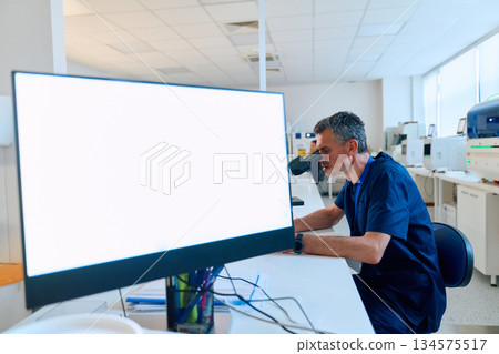 Scientist examining samples under microscope in modern laboratory setting during daytime work hours 134575517