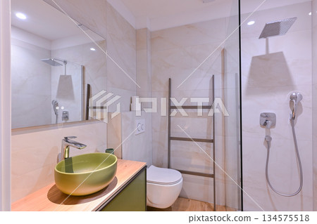 Luxurious modern bathroom featuring a sleek freestanding bathtub with a caddy, elegant vanity with sink and mirror, and a contemporary toilet. Soft tiled walls and wooden flooring create a spa-like Luxurious modern bathroom featuring a sleek freestanding bathtub with a caddy, elegant vanity with sink and mirror, and a contemporary toilet. Soft tiled walls and wooden flooring create a spa-like 134575518