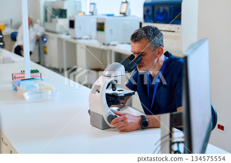 Scientist examines slide through microscope in modern laboratory setting during daytime work hours 134575554