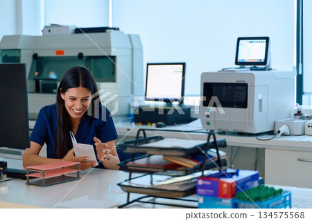 Scientist reviews data and smiles while working in a modern laboratory during the afternoon Scientist reviews data and smiles while working in a modern laboratory during the afternoon 134575568