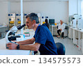Scientist focused on research using a microscope in a modern laboratory setting during the day 134575573