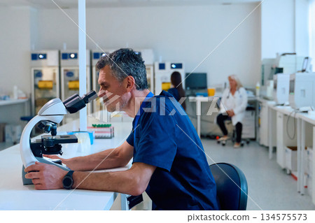 Scientist focused on research using a microscope in a modern laboratory setting during the day 134575573