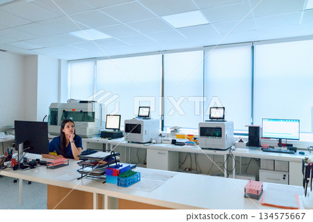 Scientist working in a modern laboratory setting with advanced equipment during the day 134575667
