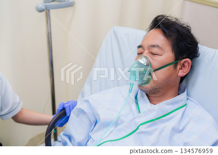 Elderly man on a ventilator in a hospital ward 134576959