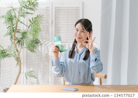 A woman looking at a passbook and smiling A woman looking at a passbook and smiling 134577027