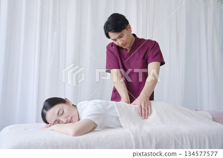 Female masseuse giving back massage Female masseuse giving back massage 134577577
