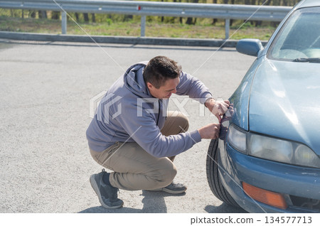 A Caucasian man tries to repair damage to a car body with his hands. A Caucasian man tries to repair damage to a car body with his hands. 134577713
