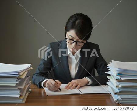 A woman is sitting at a desk writing A woman is sitting at a desk writing 134578078