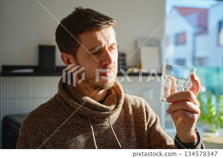 Man drinking water from glass in home kitchen closeup 134578347