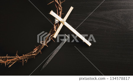 Crown of thorns, wooden cross, iron nail placed on Holy Bible, symbolizing Christian faith, sacrifice, crucifixion, Easter reflection, religion background for worship, spiritual concept 134578817