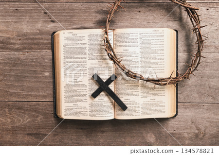 Crown of thorns with wooden cross, iron nail on Bible, symbolizing Christian faith, sacrifice, crucifixion, Easter reflection, religious background for worship, prayer, devotion concepts 134578821