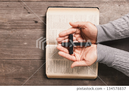 Hands in prayer above Holy Bible on wooden table, symbolizing Christian faith, worship, devotion, trust in God, spiritual religious background with copy space for church, prayer, meditation concepts. Hands in prayer above Holy Bible on wooden table, symbolizing Christian faith, worship, devotion, trust in God, spiritual religious background with copy space for church, prayer, meditation concepts. 134578837