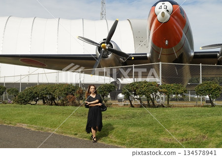Tall woman taking pictures of an airplane Tall woman taking pictures of an airplane 134578941