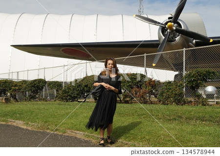 Tall woman taking pictures of an airplane Tall woman taking pictures of an airplane 134578944