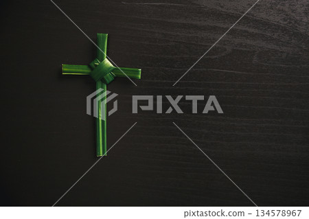 Palm leaf cross attached to crown of thorns green palm leaves on dark background symbolizing Christian faith Palm Sunday sacrifice Easter reflection religious concept for worship prayer church design 134578967